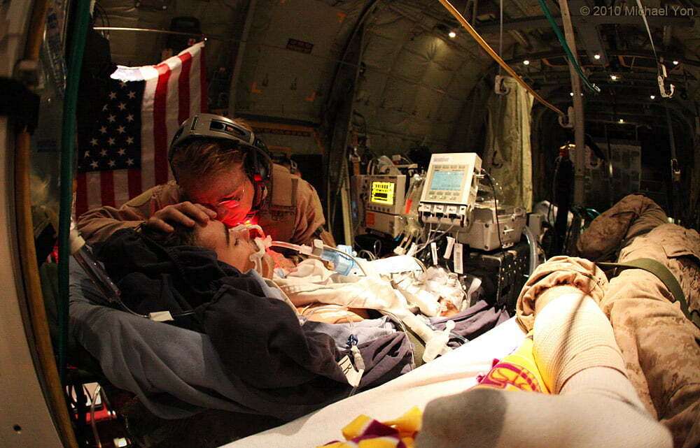 A crew from the United States Air Force spent Saturday night and Sunday morning airlifting different groups of wounded soldiers from Kandahar to Camp Bastion to Bagram, back to Kandahar, then back to Bagram, and back to Kandahar. These patients were from Afghanistan, Australia, Canada, and the United States. Here, an Air Force nurse caresses the head of a wounded, unconscious Canadian soldier while whispering into his ear.
